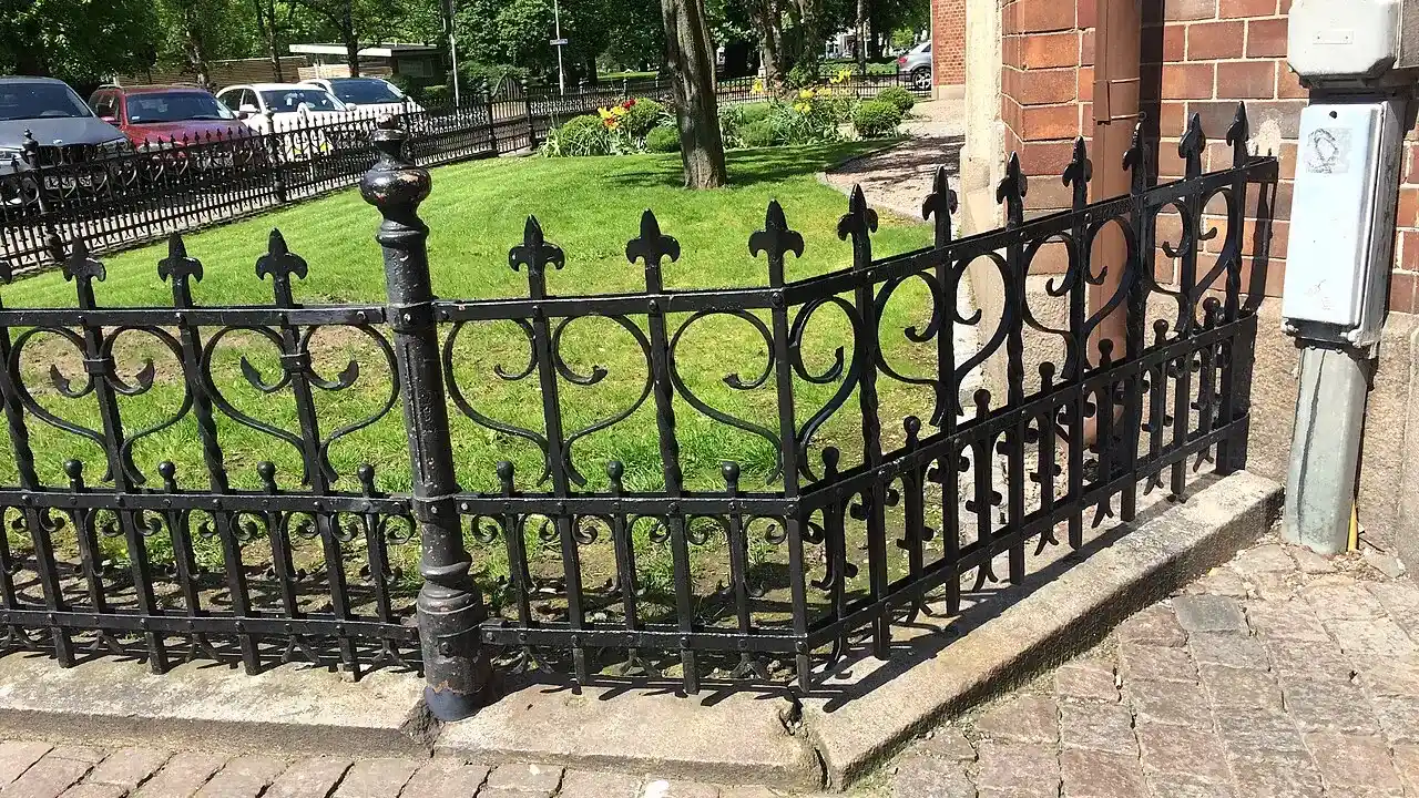 Black wrought-iron fence along a brick walkway