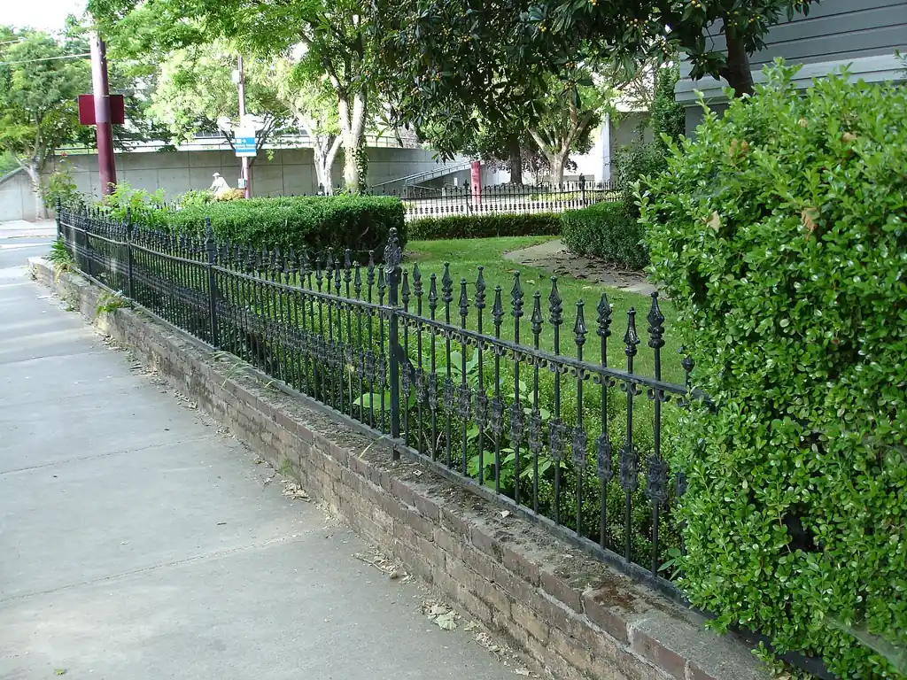 Black wrought-iron fence along a garden walk
