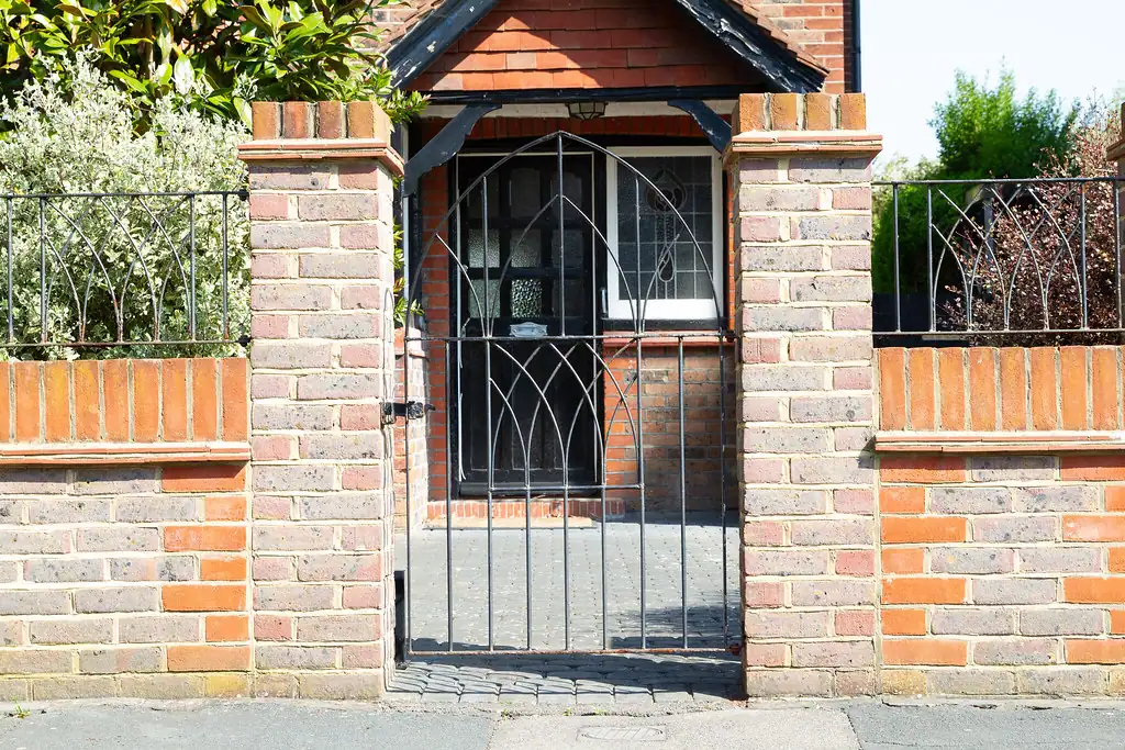 Black iron driveway gate between brick pillars