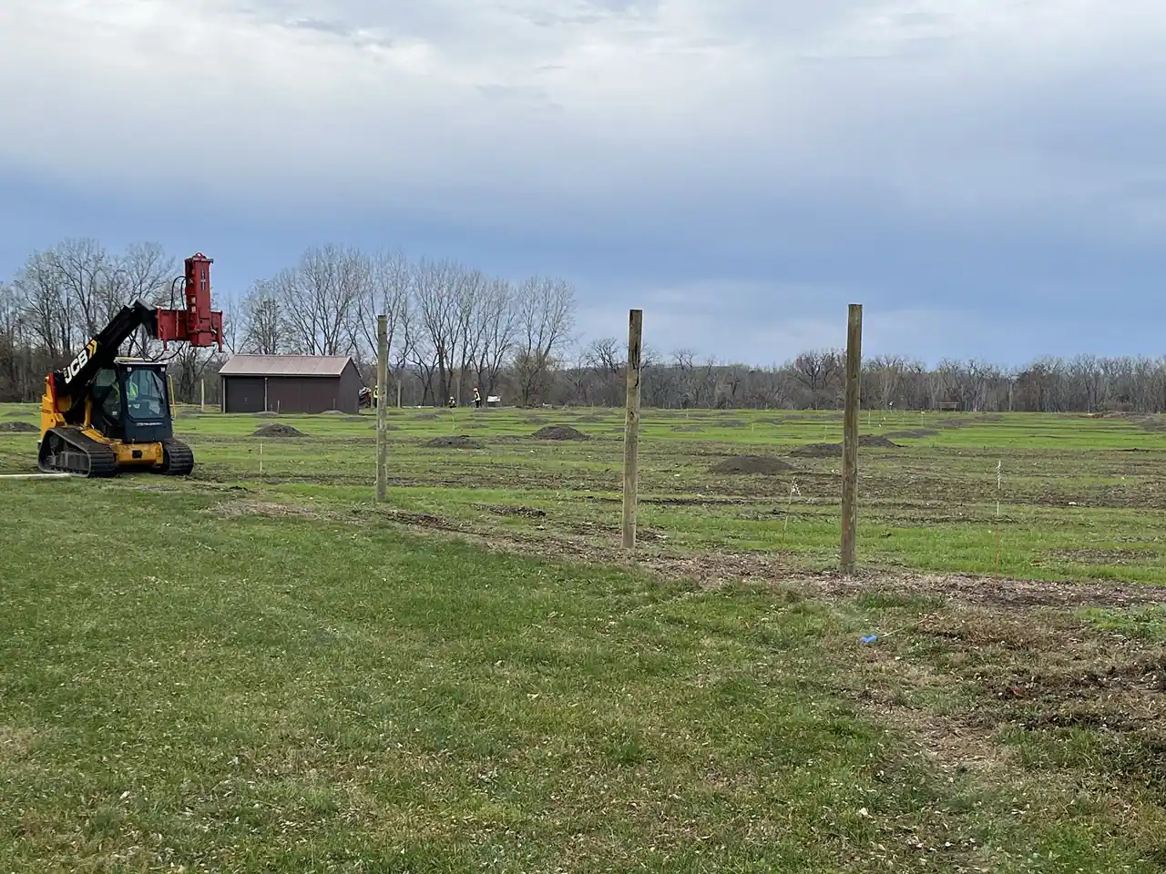 Fence posts being set in a field with a tractor