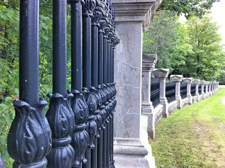 Black ornamental iron fence with stone posts